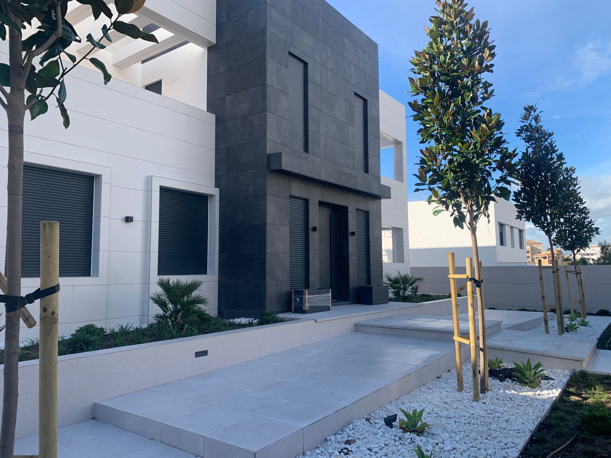 Villas Hacienda Paredes Málaga — acceso y entrada a villa, fachada oscura con jardinería