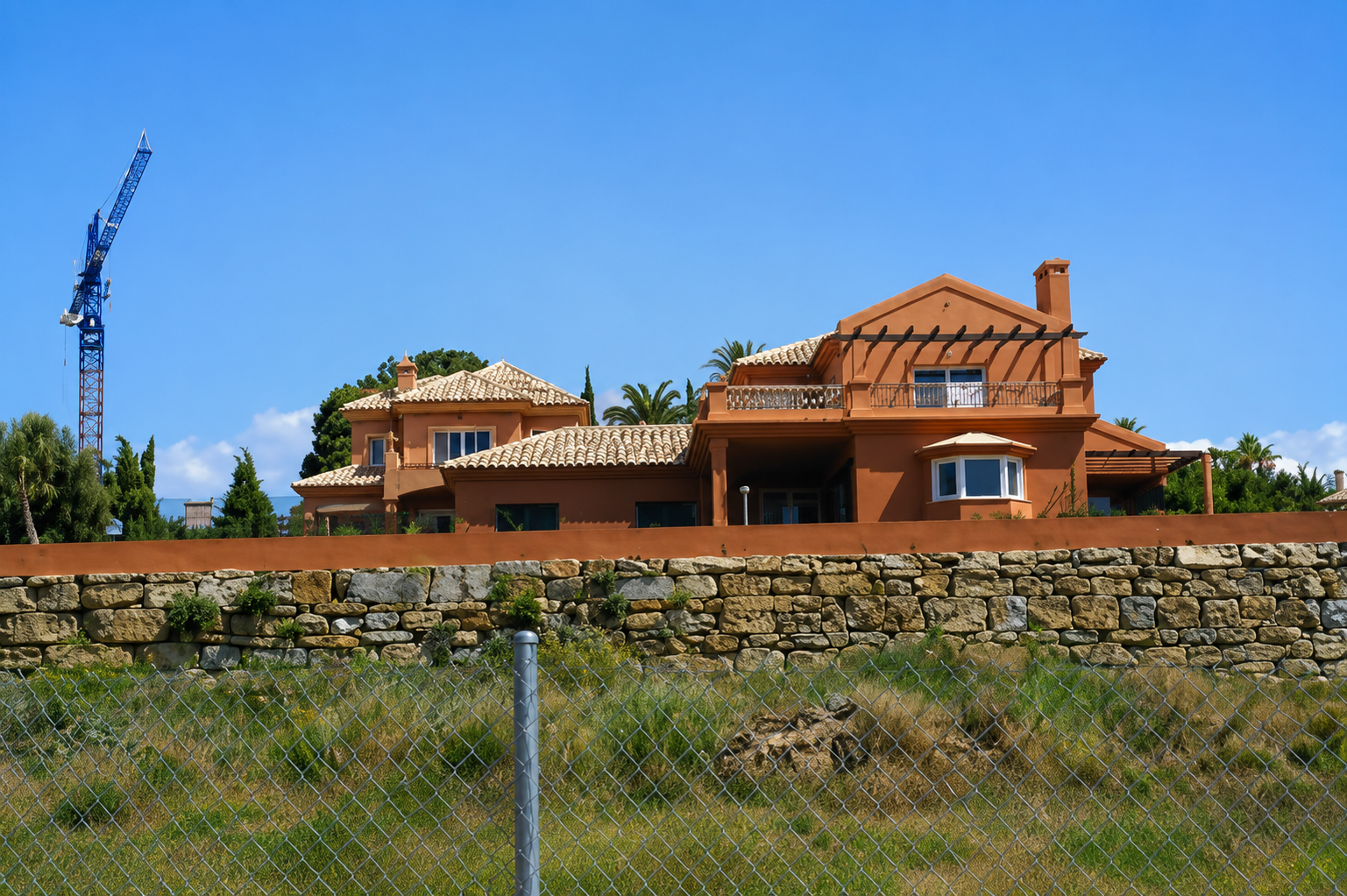 Villa terracota naranja en construcción con grúa, Costa del Sol Málaga